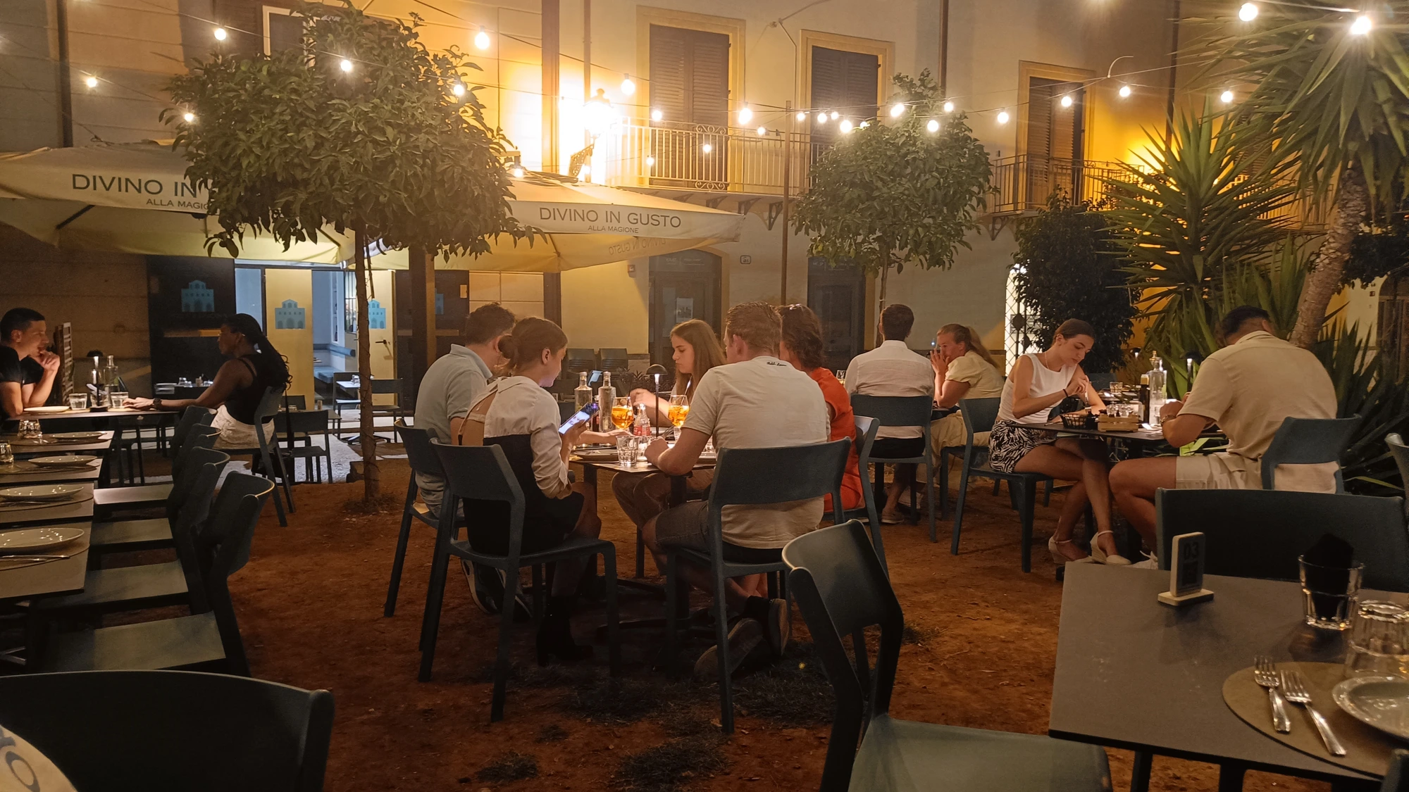 Gemeinsames Abendessen in einem sizilianischen Restaurant unter Lichterketten